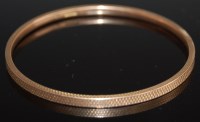 Lot 2001 - A 9ct gold bangle having engine turned...