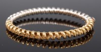 Lot 1188 - An 18ct yellow and white gold hinged bangle,...