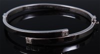 Lot 1185 - A modern 9ct white gold hinged bangle, the...