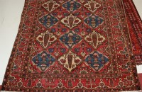 Lot 1576 - A Persian woollen rug, the rust coloured field...