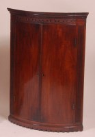 Lot 801 - A George III mahogany bowfront hanging corner...