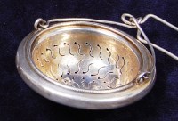 Lot 164 - An antique silver tea strainer, having swing...