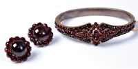 Lot 2155 - A garnet bangle and earrings, central garnet...
