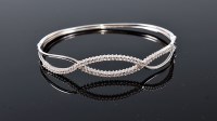Lot 1163 - A diamond set hinged bangle, comprising of two...