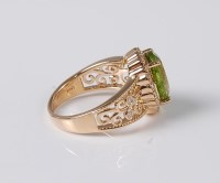Lot 1187 - A peridot and diamond ring, the oval peridot...
