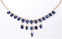 Lot 1157 - A '21k' sapphire fringe necklace, the oval...