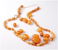 Lot 2183 - A butterscotch amber bead necklace, the oval...
