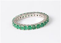 Lot 2561 - An 18ct white gold emerald eternity ring, the...