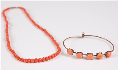 Lot 1301 - A coral bead necklace and a coral bangle, the...