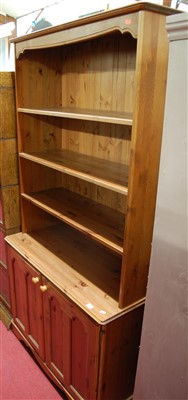 Lot 1201 - A modern pine effect bookcase cupboard, having...