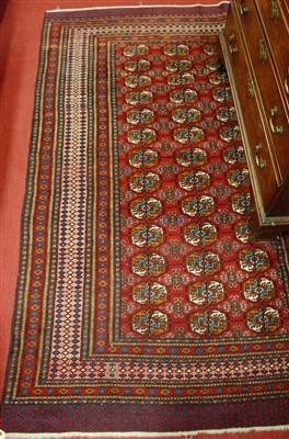 Lot 1134 - A Persian woollen red ground Bokhara rug,...