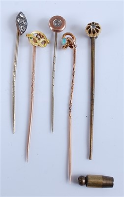 Lot 2552 - A collection of five yellow metal stick pins,...