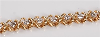 Lot 1219 - A yellow metal diamond line bracelet, the...