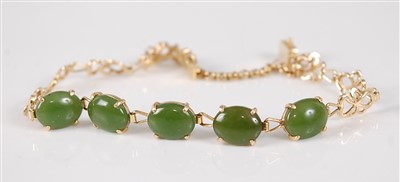 Lot 2679 - A yellow metal and jade set bracelet, arranged...