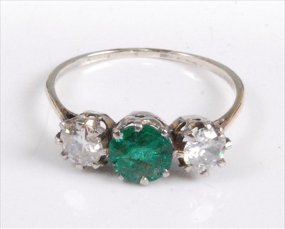 Lot 1193 - A white metal, emerald and diamond three-stone...