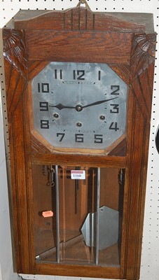 Lot 1160 - A 1930s oak droptrunk wall clock, having a...