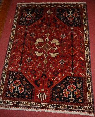 Lot 1179 - An Iranian woollen red ground rug, the central...
