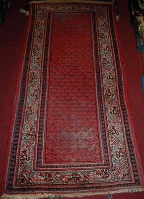 Lot 1180 - A Persian woollen red ground rug, 210 x 110cm;...