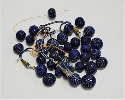 Lot 478 - A collection of carved lapis lazuli beads, the...