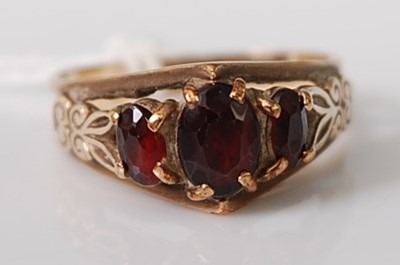 Lot 302 - A 9ct yellow gold three-stone garnet dress...