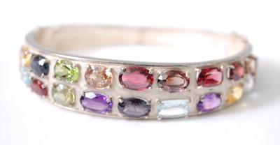 Lot 2582 - A white metal multi-stone oval hinged bangle,...