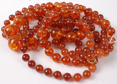 Lot 419 - A clear orange amber beaded and knotted...