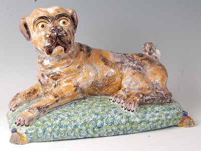 Lot 2063 - A French faience model of a recumbent pug dog...