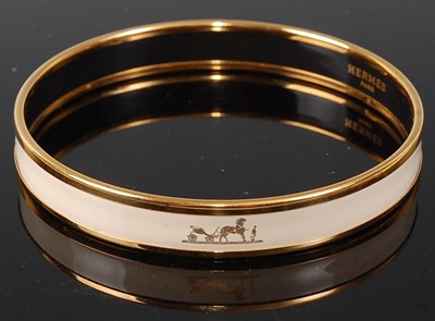 Lot 160 - A Hermès gold plated and printed white enamel...