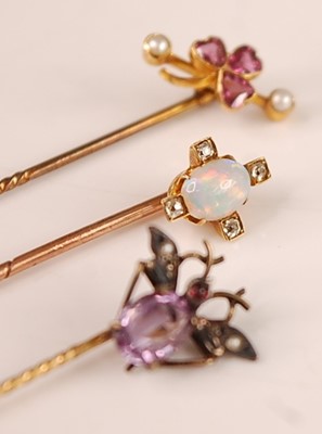 Lot 3120 - Three stick pins: A yellow metal pin as a...