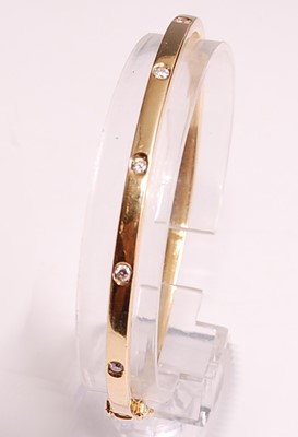 Lot 1099 - An 18ct yellow gold oval hinged diamond bangle,...