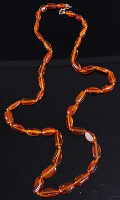 Lot 456 - A clear orange amber necklace, 64cm