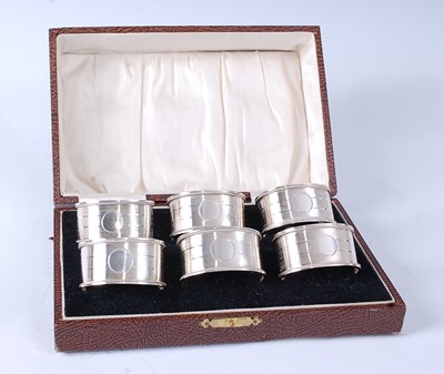 Lot 1103 - A cased set of six George V silver napkin...