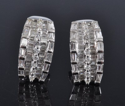 Lot 1168 - A pair of white metal diamond half hoop...
