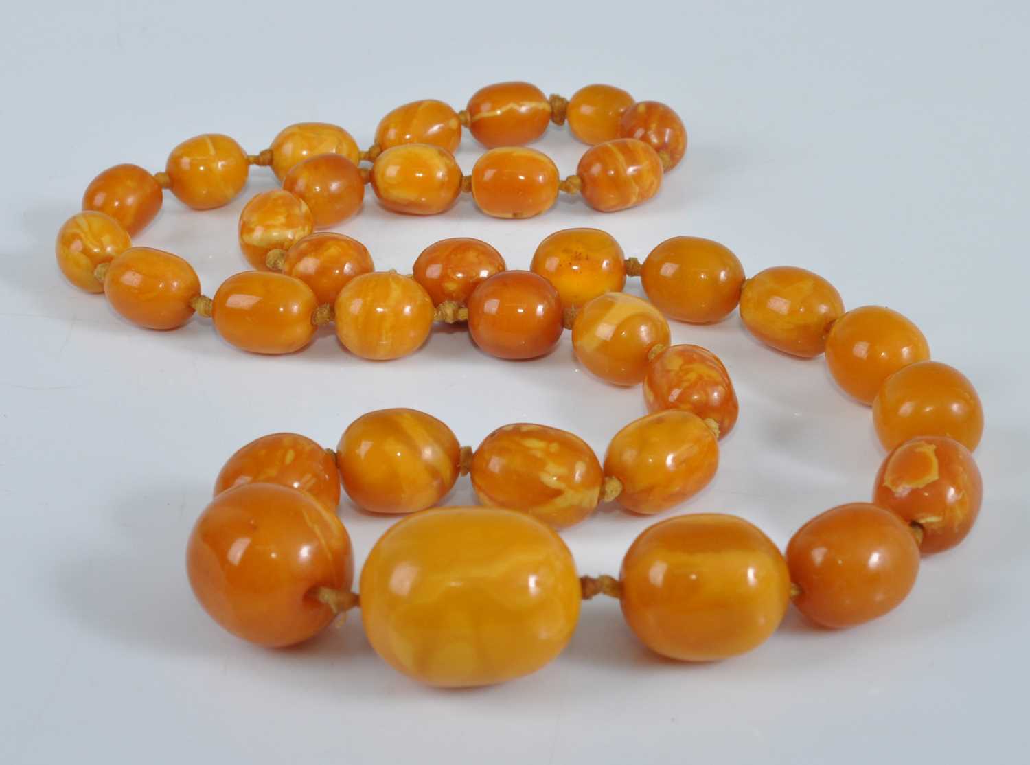 Lot 1184 - An amber single string necklace, the graduated...