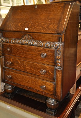 Lot 1266 - A 1930s floral moulded oak slopefront three...