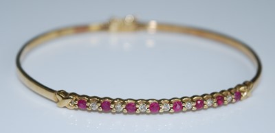 Lot 2569 - A yellow metal, ruby and diamond oval hinged...