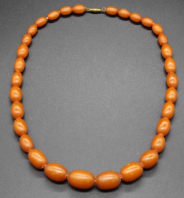 Lot 510 - A faux amber single string necklace, arranged...