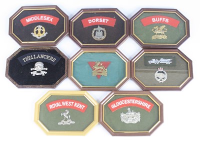 Lot 561 - A collection of cap badges, mounted with cloth...