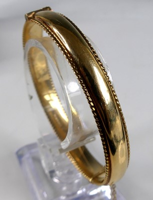 Lot 2624 - A modern 9ct gold hinged bangle, having...