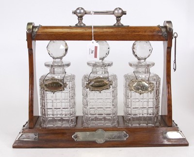 Lot 36 - An Edwardian oak three bottle tantalus having...