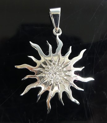 Lot 2588 - A white metal sun pendant, having a centre...