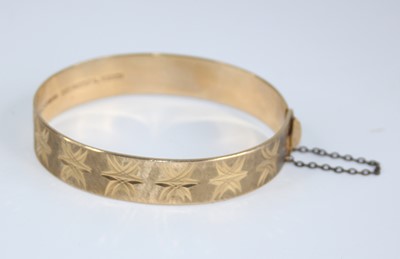 Lot 2486 - A 9ct gold hinged bangle, having bright cut...