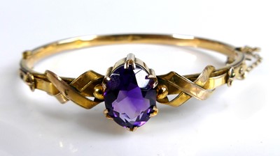 Lot 313 - A 9ct yellow gold amethyst hinged oval bangle...