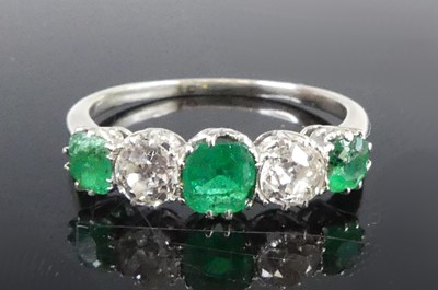 Lot 1187 - A white metal emerald and diamond half-hoop...