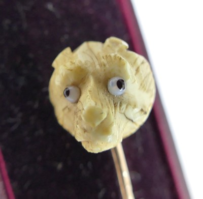 Lot 2585 - A yellow metal and carved bone stick pin...