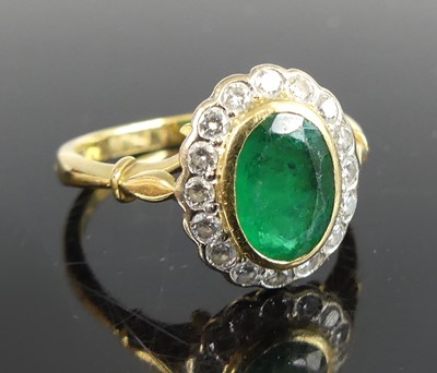 Lot 2607 - An 18ct gold emerald and diamond oval cluster...