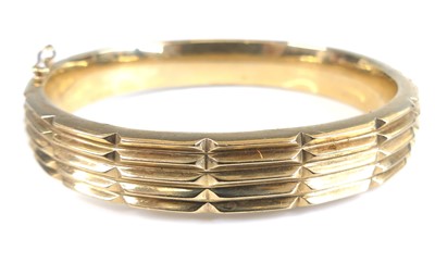 Lot 2698 - A 9ct gold hinge bangle, in raised and reeded...