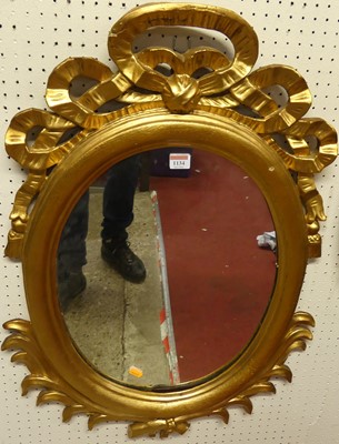 Lot 1134 - A gilt framed oval wall mirror, with ribbon...