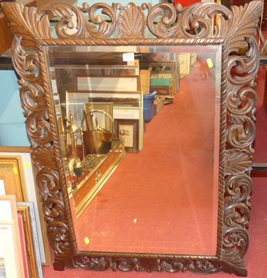 Lot 1062 - A circa 1900 carved oak framed and bevelled...