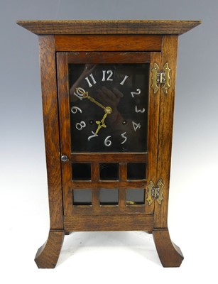 Lot 176 - An Arts & Crafts oak mantel clock, the glazed...